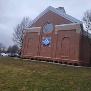 A brick building with a circular window and a banner, set against a cloudy sky.