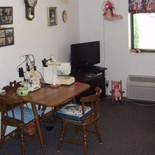 A cozy sewing room with a table, chairs, and a television.