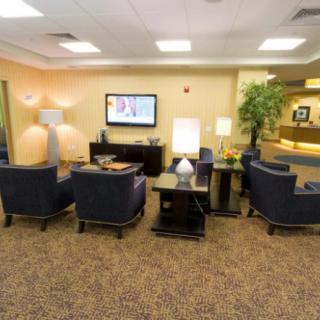 A cozy waiting room featuring comfortable chairs, a television, and ambient lighting.
