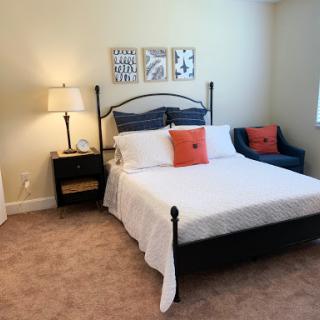 A cozy bedroom featuring a neatly made bed, decorative pillows, and stylish wall art.