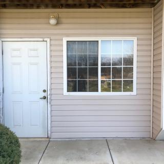 Exterior view of a house entrance with a white door and adjacent window.