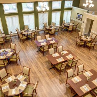 An elegant dining room with neatly arranged tables and chairs on a wooden floor.