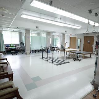 A spacious and well-lit rehabilitation room equipped for physical therapy.