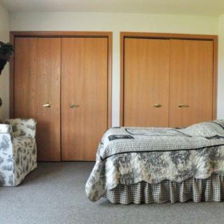 A simple bedroom with a bed, carpet, and double closets.