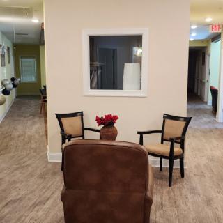 A cozy lobby seating area with chairs and a small table topped with flowers.
