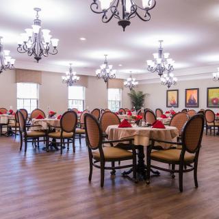 A spacious dining room with elegant chandeliers and neatly arranged tables set for dining.