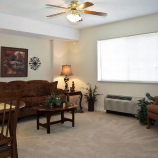 A cozy living room with a sofa, coffee table, lamp, and a large window.