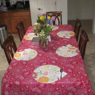 A dining table set with a colorful tablecloth and floral centerpiece.