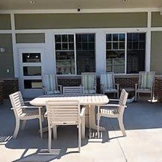 An outdoor patio setup with a table and several chairs arranged on a concrete surface.
