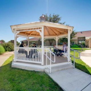 A charming white gazebo in a sunny park setting.