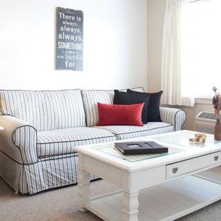 A cozy living room with a striped sofa and a white coffee table, adorned with colorful throw pillows and wall art.