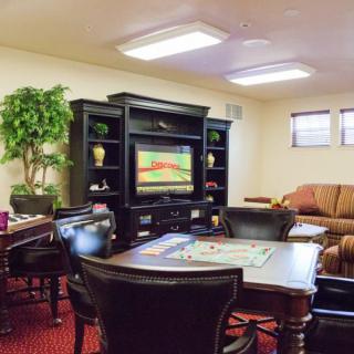 A cozy living room with a television, game table, and comfortable seating.