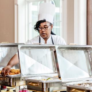 A chef preparing a buffet setup with various dishes.
