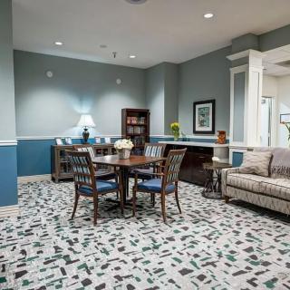 A cozy living and dining area featuring a round wooden table surrounded by chairs, a comfortable sofa, and a bookshelf in the corner.
