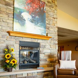A cozy living space with a stone fireplace, colorful artwork, and sunflowers in a vase.