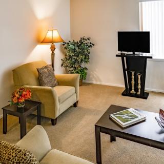 A cozy living room with armchairs, a coffee table, and a television.