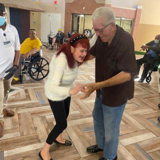 An elderly couple joyfully dancing together in a nursing home.