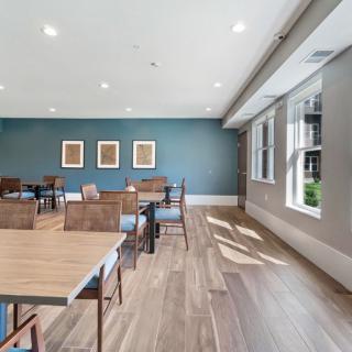 A spacious dining area with wooden floors, modern tables and chairs, and artwork on the walls.