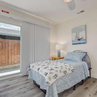 A minimalist bedroom with a single bed and nautical-themed decor, featuring a large window providing ample natural light.