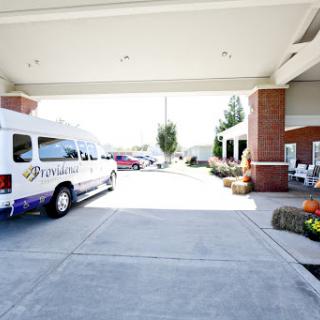 A view of the entrance to a facility with a parked van and a well-maintained exterior.