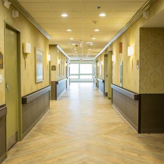 A well-lit hallway with multiple doors and a polished floor.