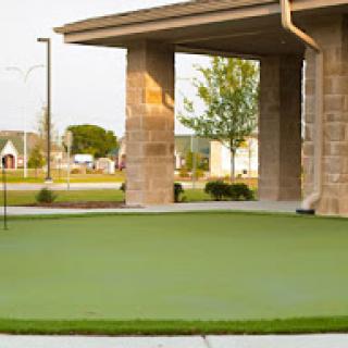 A well-maintained putting green situated near a stone structure, perfect for outdoor recreational activities.