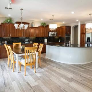 A spacious modern kitchen with wooden cabinets and a dining area, featuring an open floor plan.