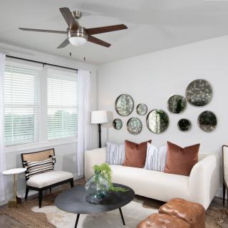 A modern living room with white walls, accented by circular mirrors and a comfortable sofa.