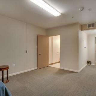 A minimalist empty room with a doorway and overhead lighting.
