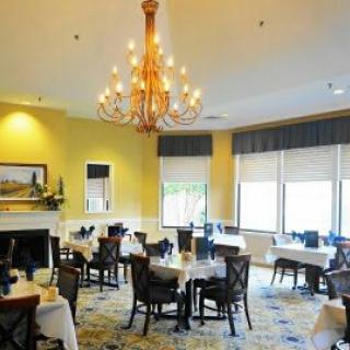 An elegant restaurant dining room with a chandelier and neatly arranged tables and chairs.