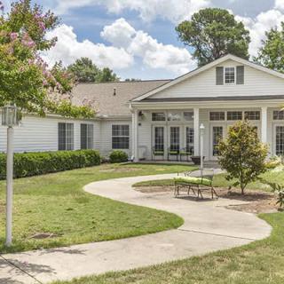 A charming single-story house with a well-maintained lawn and a curved pathway leading to the entrance.