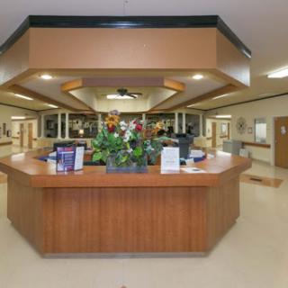 A welcoming reception area of a hospital, featuring a wooden front desk and decorative flowers.