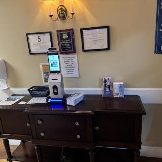 A reception area featuring a technology device for sanitization along with displayed certificates.