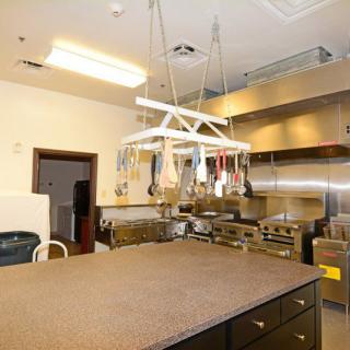 A well-equipped commercial kitchen with hanging utensils and stainless steel appliances.