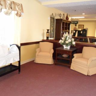 A cozy living room with armchairs, a central table adorned with a flower arrangement, and soft lighting.