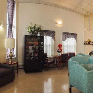 A cozy lounge area featuring comfortable seating, a bookshelf, and decorative elements.