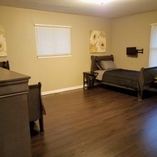 A spacious bedroom with a single bed and hardwood flooring.
