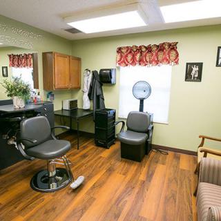 A cozy hair salon interior with a barber chair, hair dryer, and waiting area.