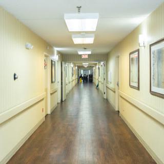 A well-lit corridor in a building, featuring wooden flooring and soft-colored walls.
