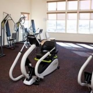 A well-lit gym with various exercise equipment.