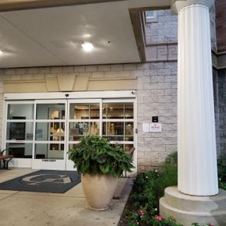 The welcoming entrance of a hotel, featuring a classic column and decorative plant.