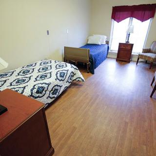 A cozy bedroom with two beds, a window, and wooden flooring.