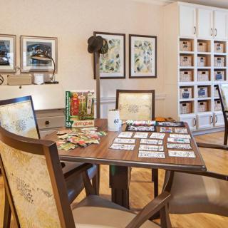 A cozy game room with a table set up for solving puzzles, surrounded by comfortable chairs and decorated with artwork on the walls.