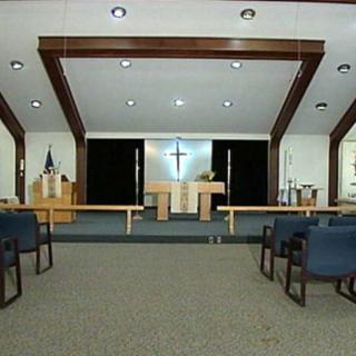 A view of a church interior with an altar and seating areas.