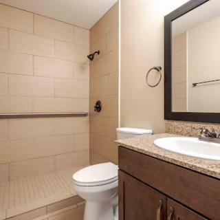 A clean and modern bathroom featuring a shower, toilet, and vanity with a mirror.