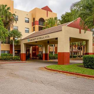 A welcoming entrance to a multi-story building surrounded by greenery.