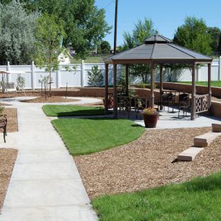 A beautifully landscaped garden featuring a gazebo and paved pathways under a sunny sky.