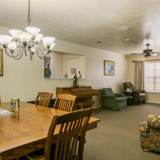 A cozy dining and living area featuring a wooden dining table with chairs, a chandelier, and a comfortable seating arrangement.