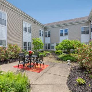 A peaceful courtyard with outdoor seating and lush greenery between residential buildings.