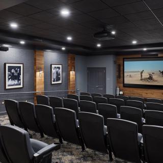 A modern home theater with multiple rows of seating and a large projector screen.